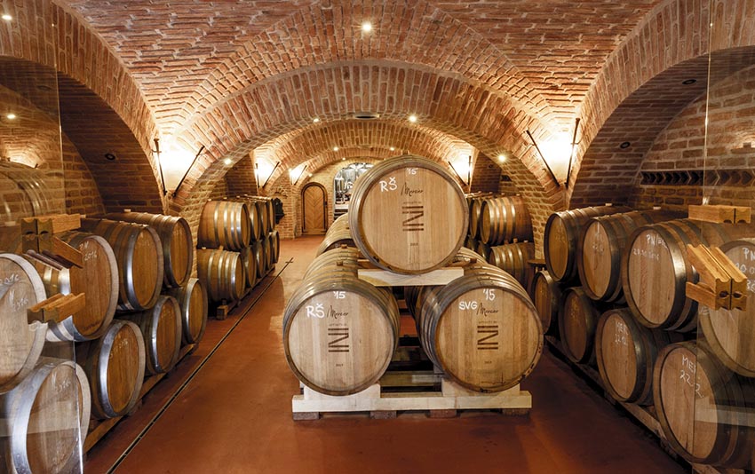 Vínne sudy vinárstva Zápražný naukladané na sebe v peknej vínnej pivnici